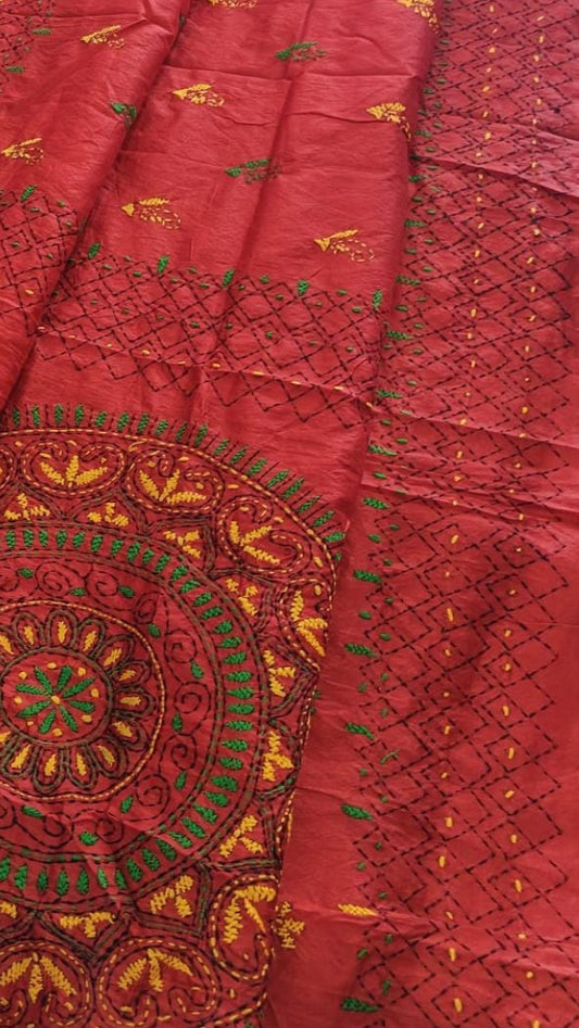 A red embroidered saree features intricate gold, green, and yellow embroidery, including a large circular mandala design.