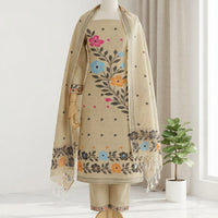 A beige three-piece traditional outfit  featuring a kurta with colorful floral embroidery, matching trousers, and a coordinating dupatta.