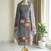 A gray embroidered dress with a matching gray shawl draped over the shoulders. The fabric features colorful floral embroidery in red, yellow, blue, and white.