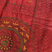 A red embroidered saree features intricate gold, green, and yellow embroidery, including a large circular mandala design.