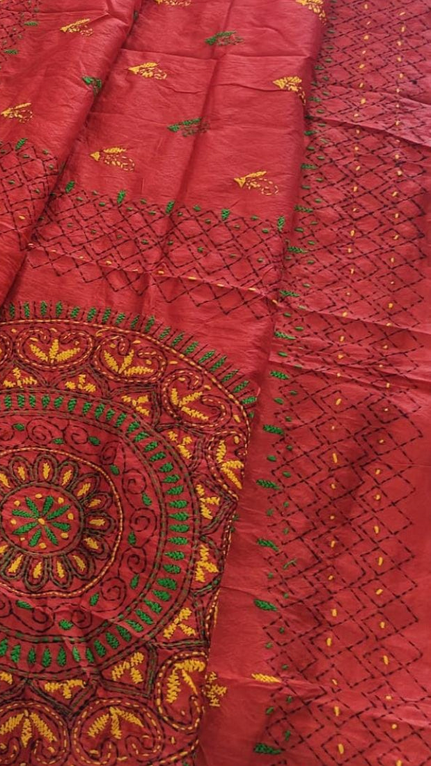 A red embroidered saree features intricate gold, green, and yellow embroidery, including a large circular mandala design.